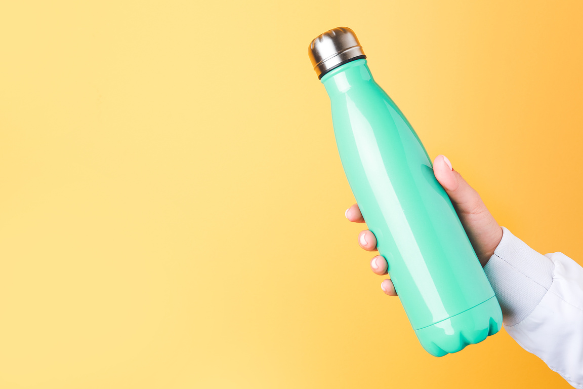 Female Hand with Sports Water Bottle on Color Background